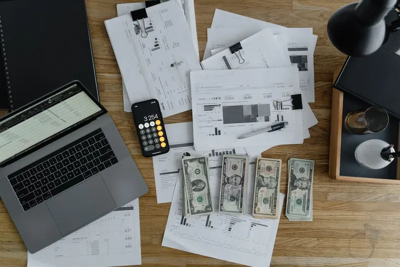 Laptop, calculadora y reportes para proyectar el flujo de caja de una empresa